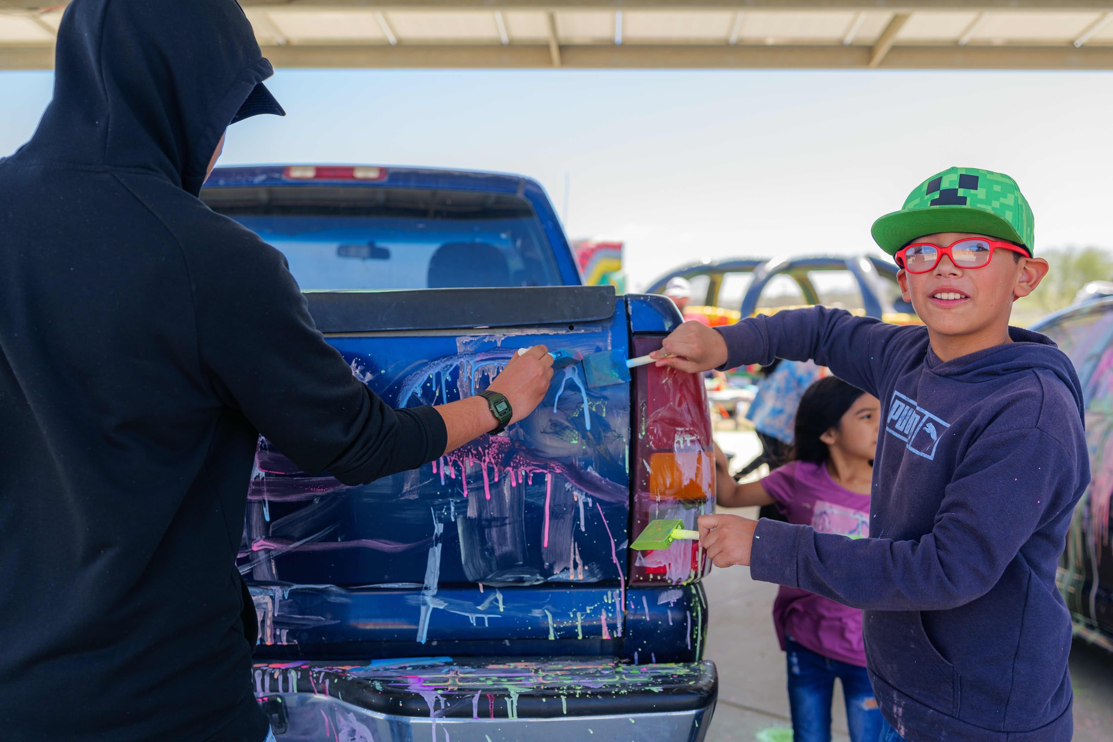 Kids painting a truck at a community event