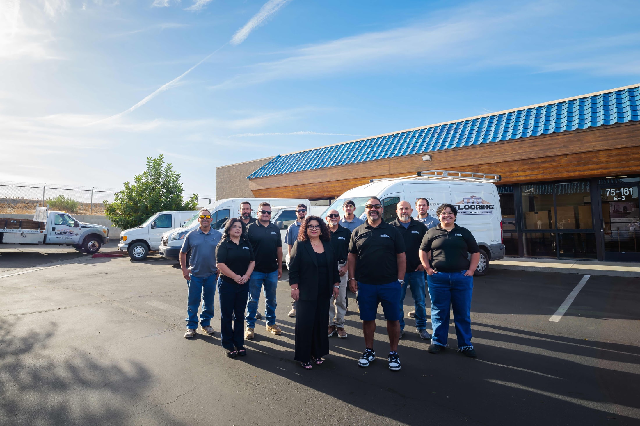 P&R Flooring company team photo in front of their vans and storefront