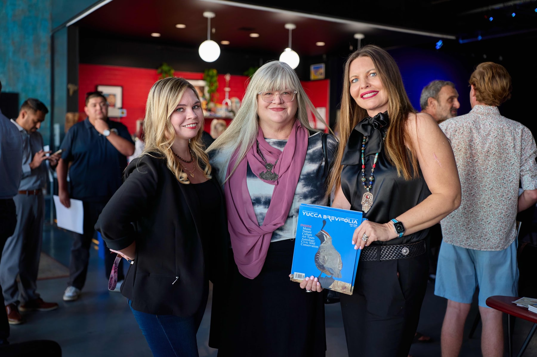 Three women holding a copy of Yucca Brevifolia at the launch