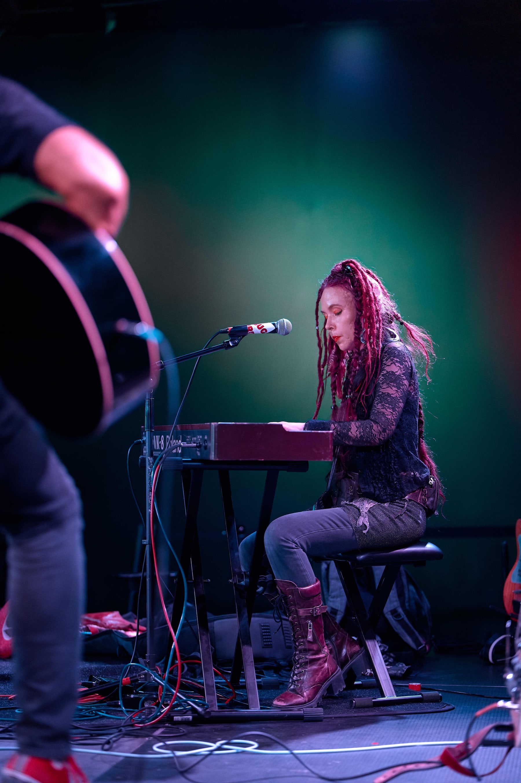 Musician at a keyboard under green stage light at The Firebug