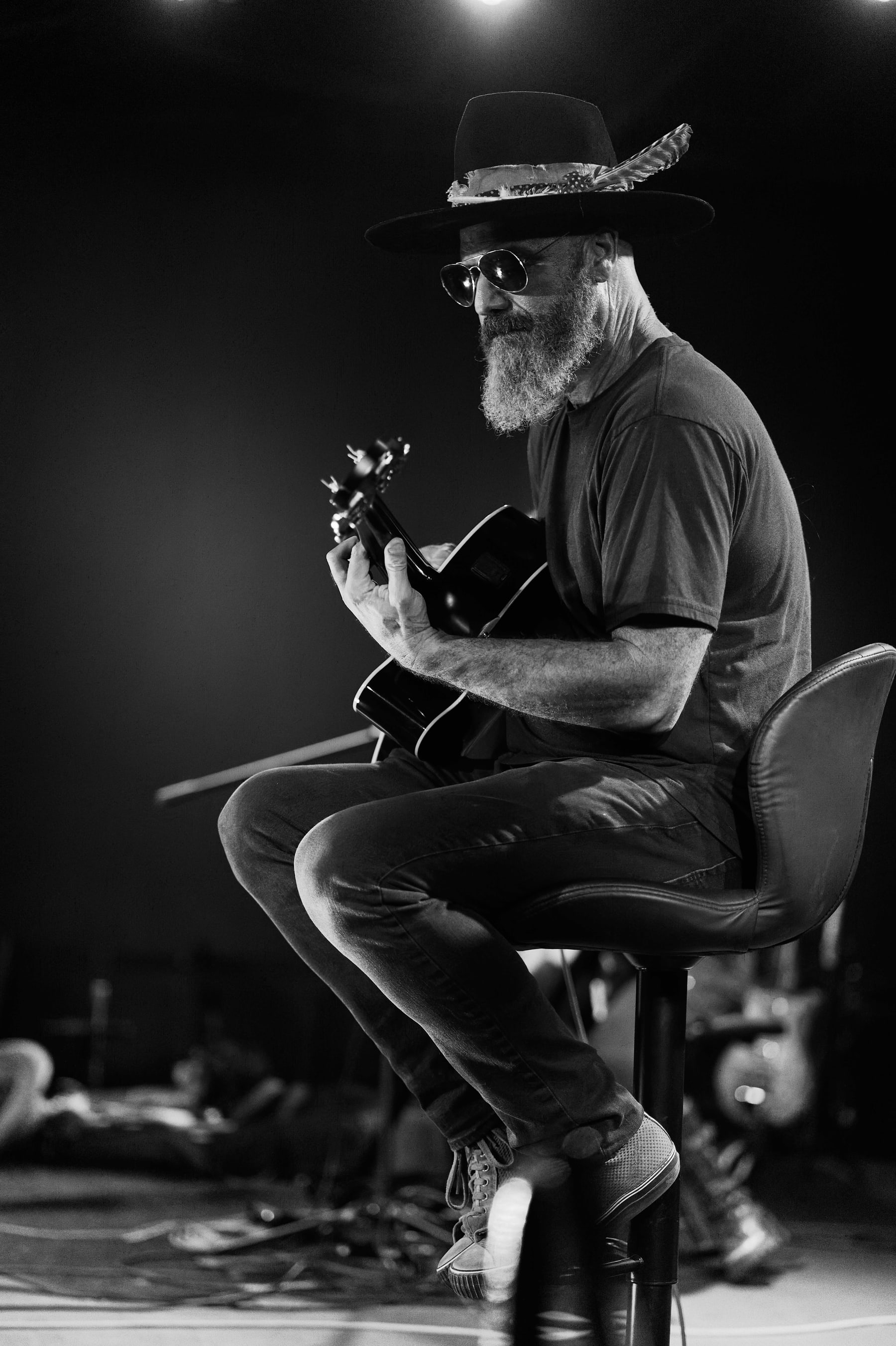 Black and white frame of a guitarist seated under stage light