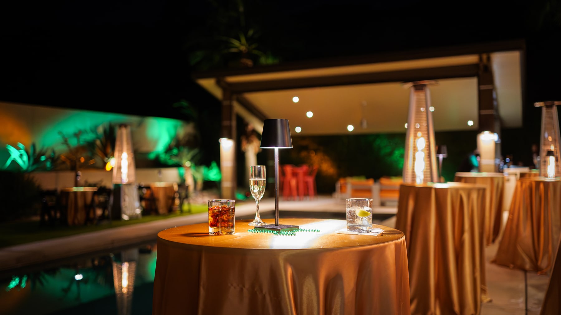 Cactus Club terrace set for the evening, lit green with the tables laid