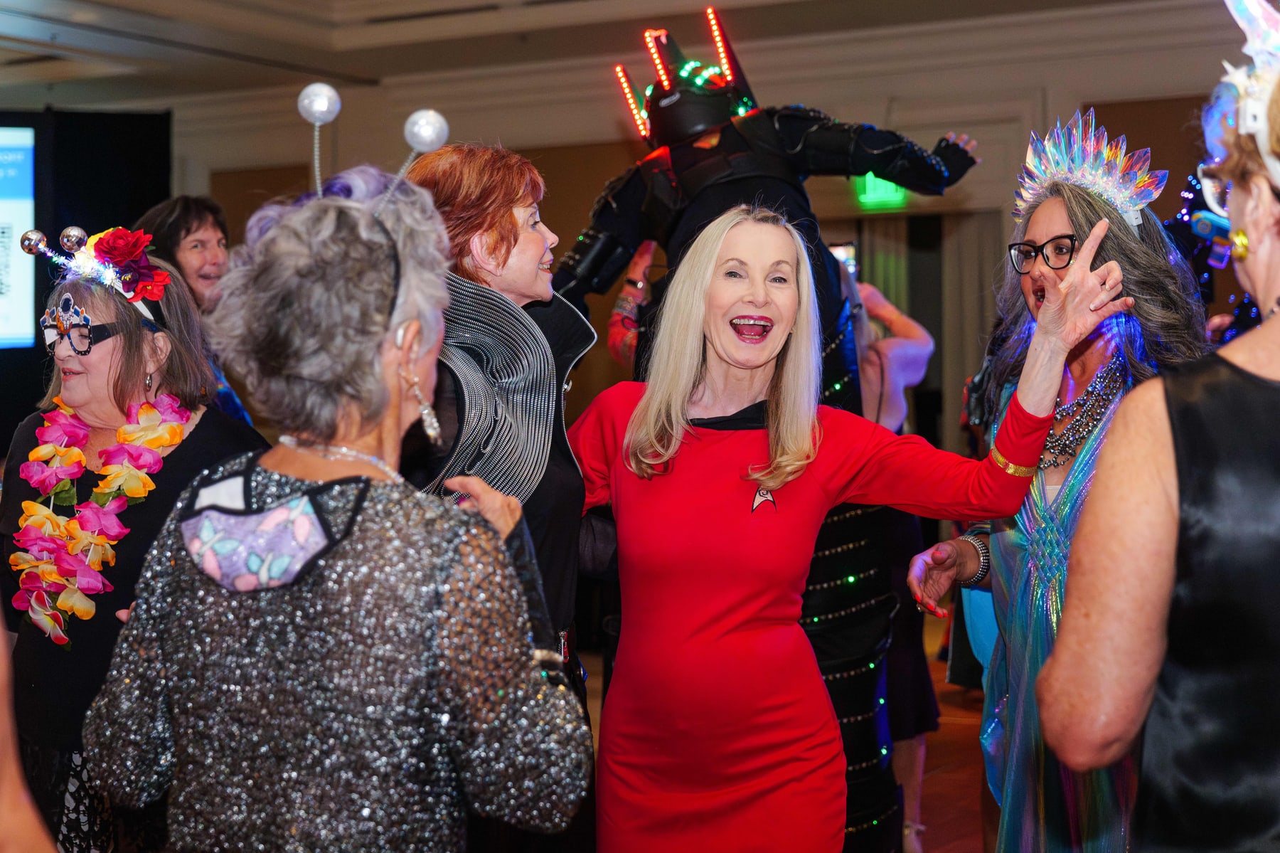 Guests laughing in feathered headpieces at the Out of This World Gala