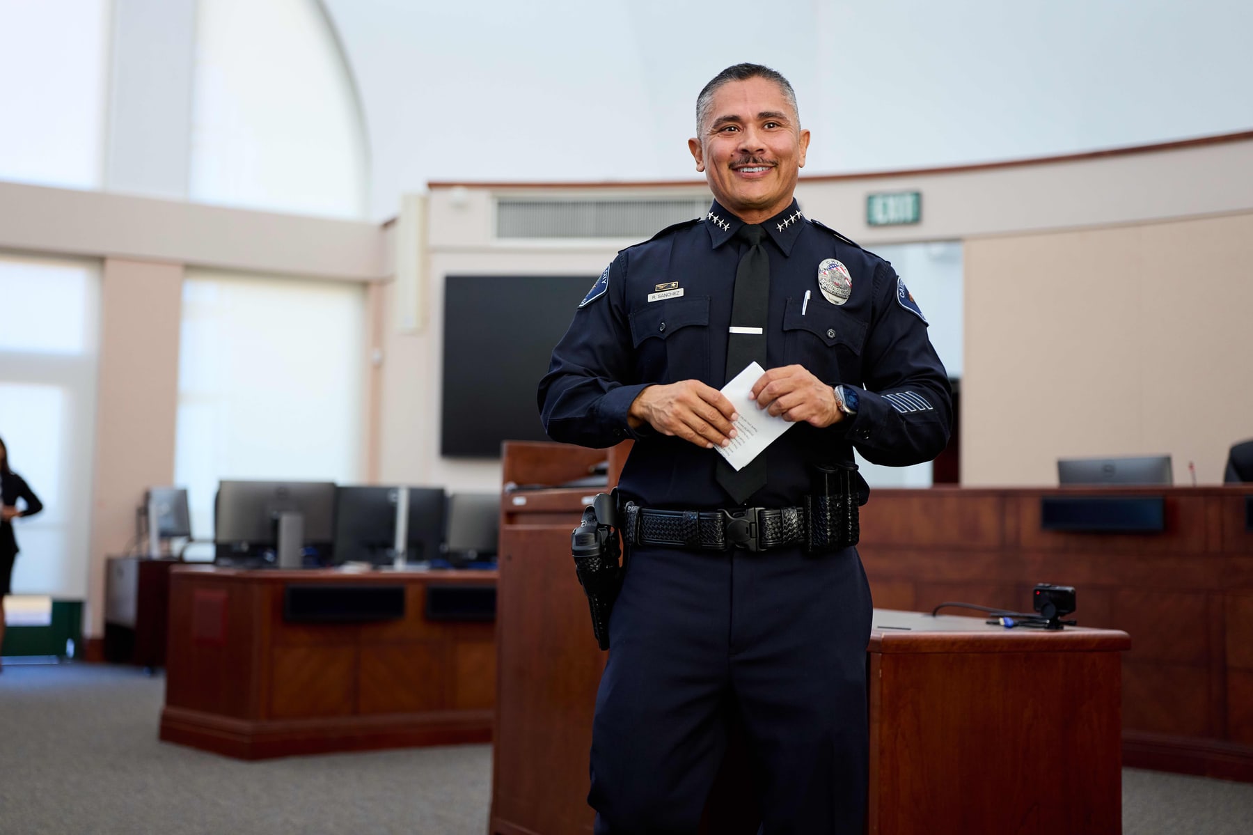 An officer holding his certificate in the council chamber