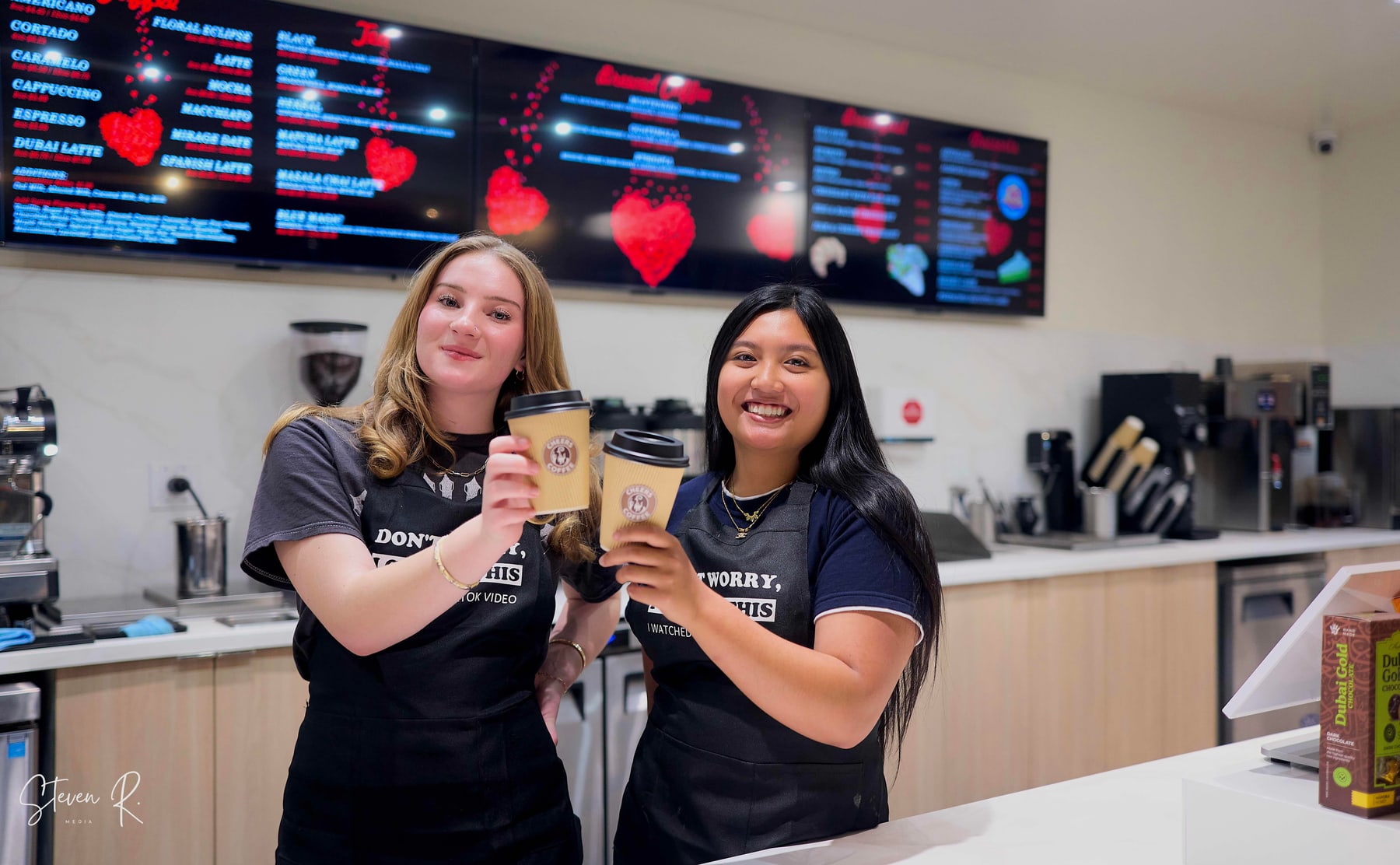 Two of the Cheers Coffee team toasting behind the counter