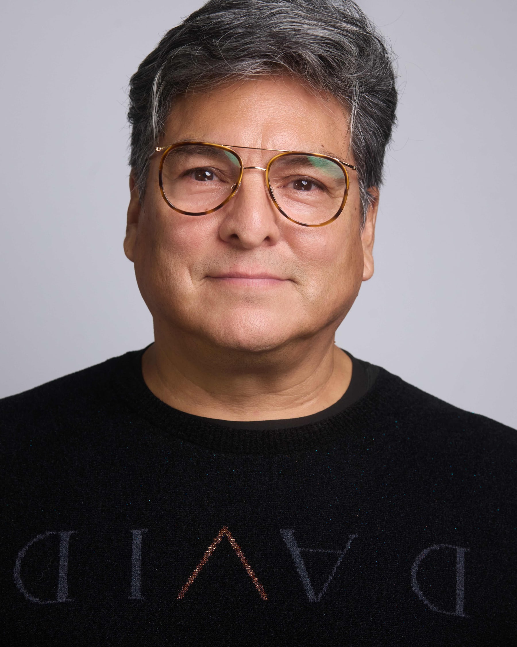 Studio headshot of a man in glasses against a pale backdrop