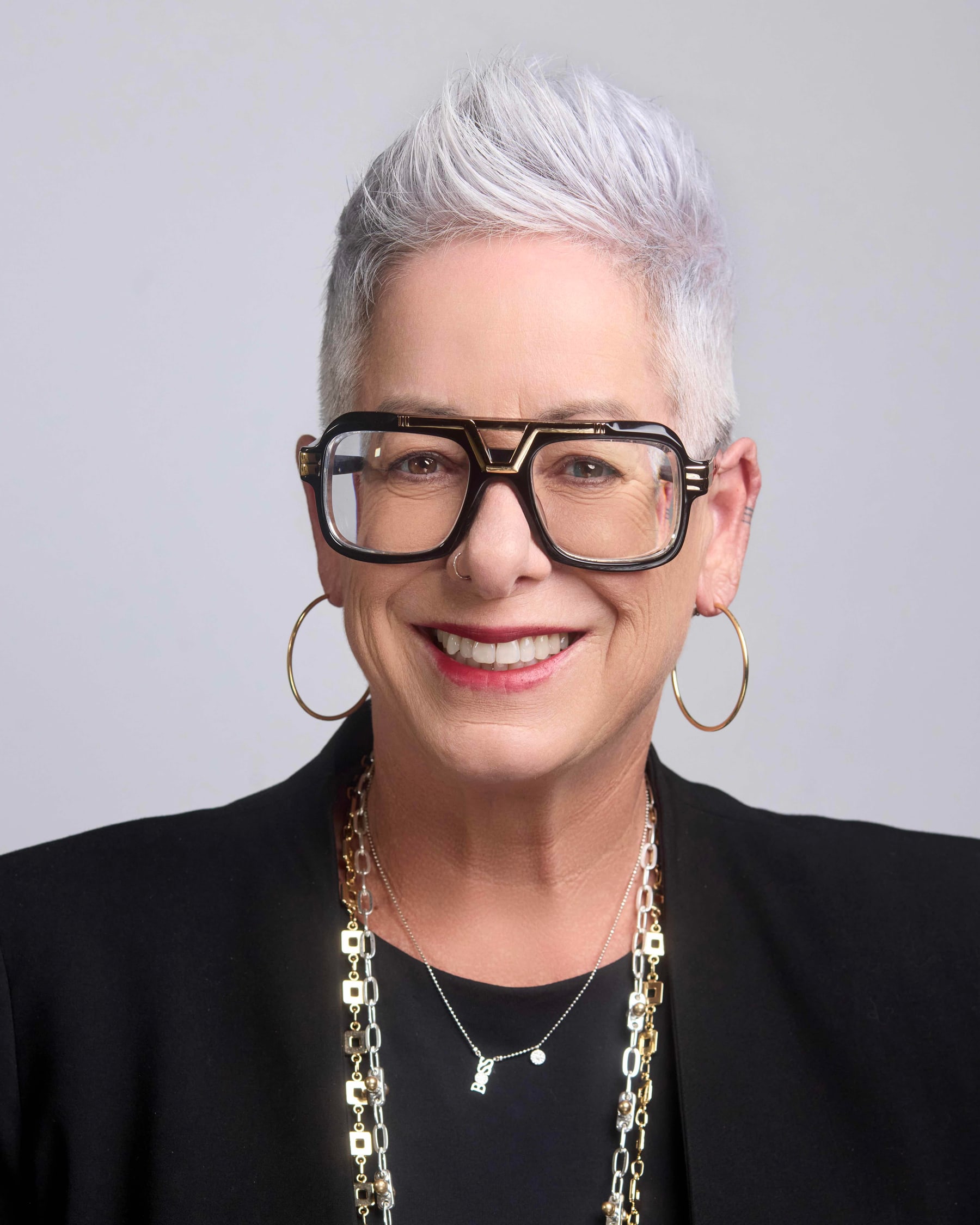 Studio headshot of a woman with silver hair and bold glasses