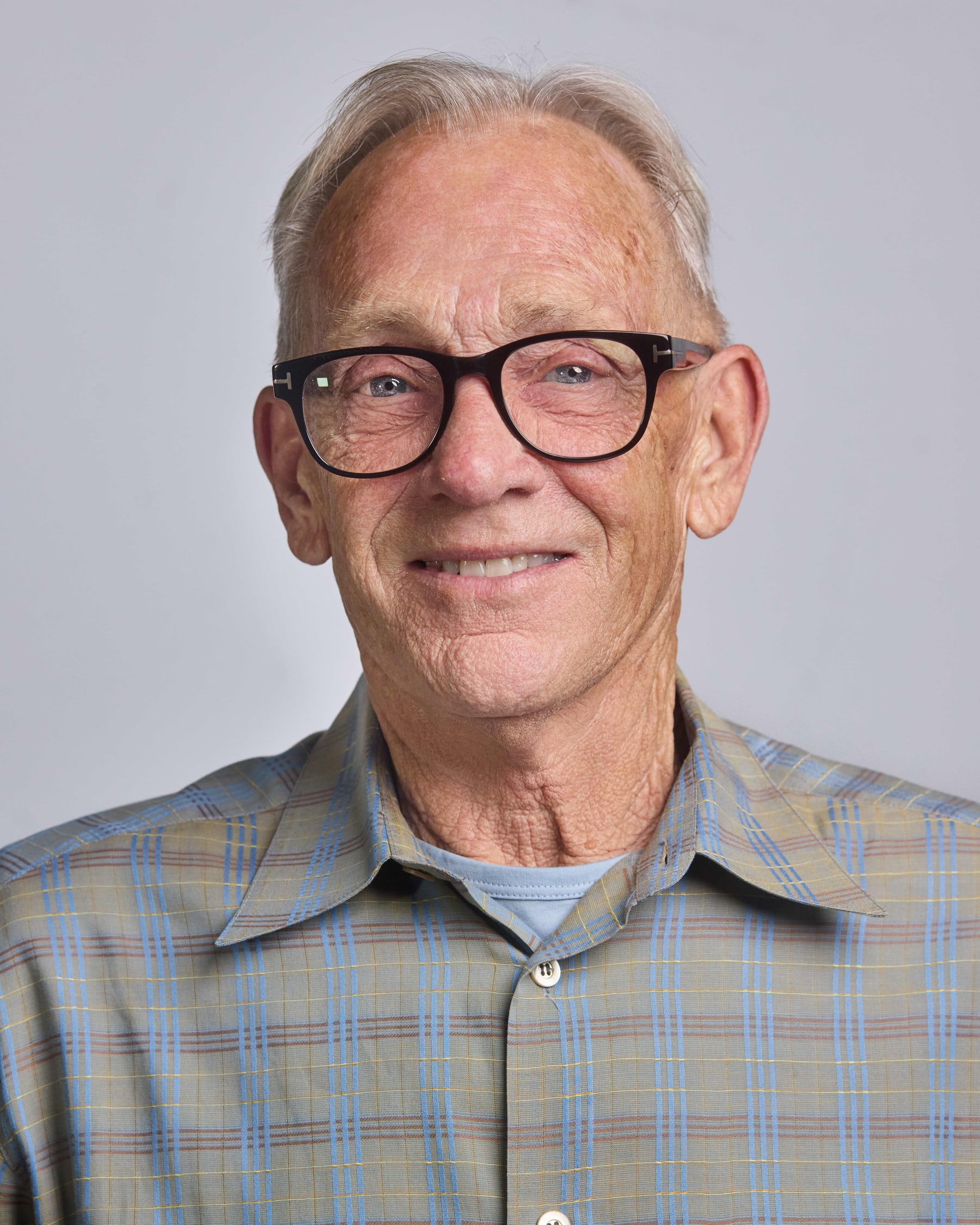 Studio headshot of a man in a checked shirt
