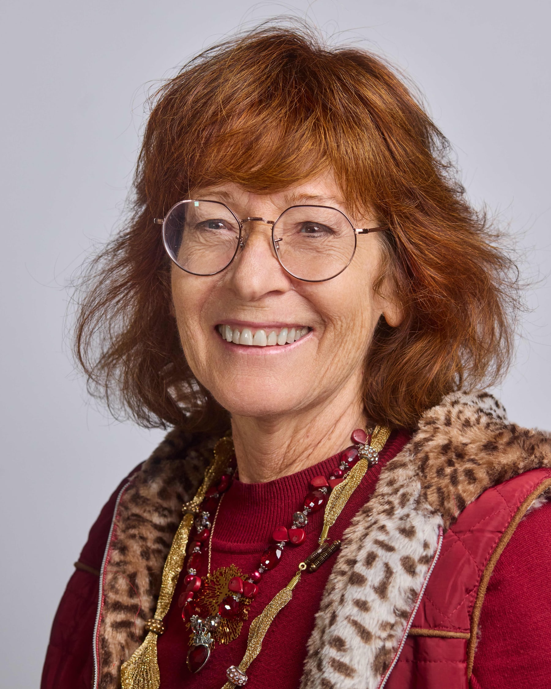 Studio headshot of a woman with red hair and a patterned scarf