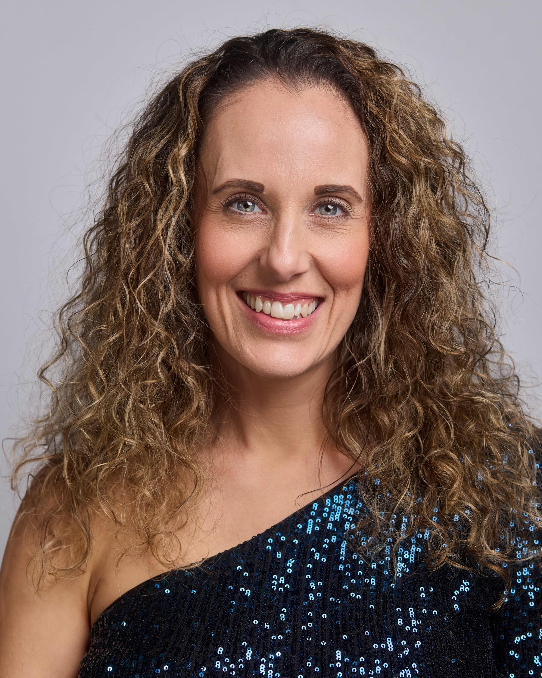 Studio headshot of a woman in a sequinned dress