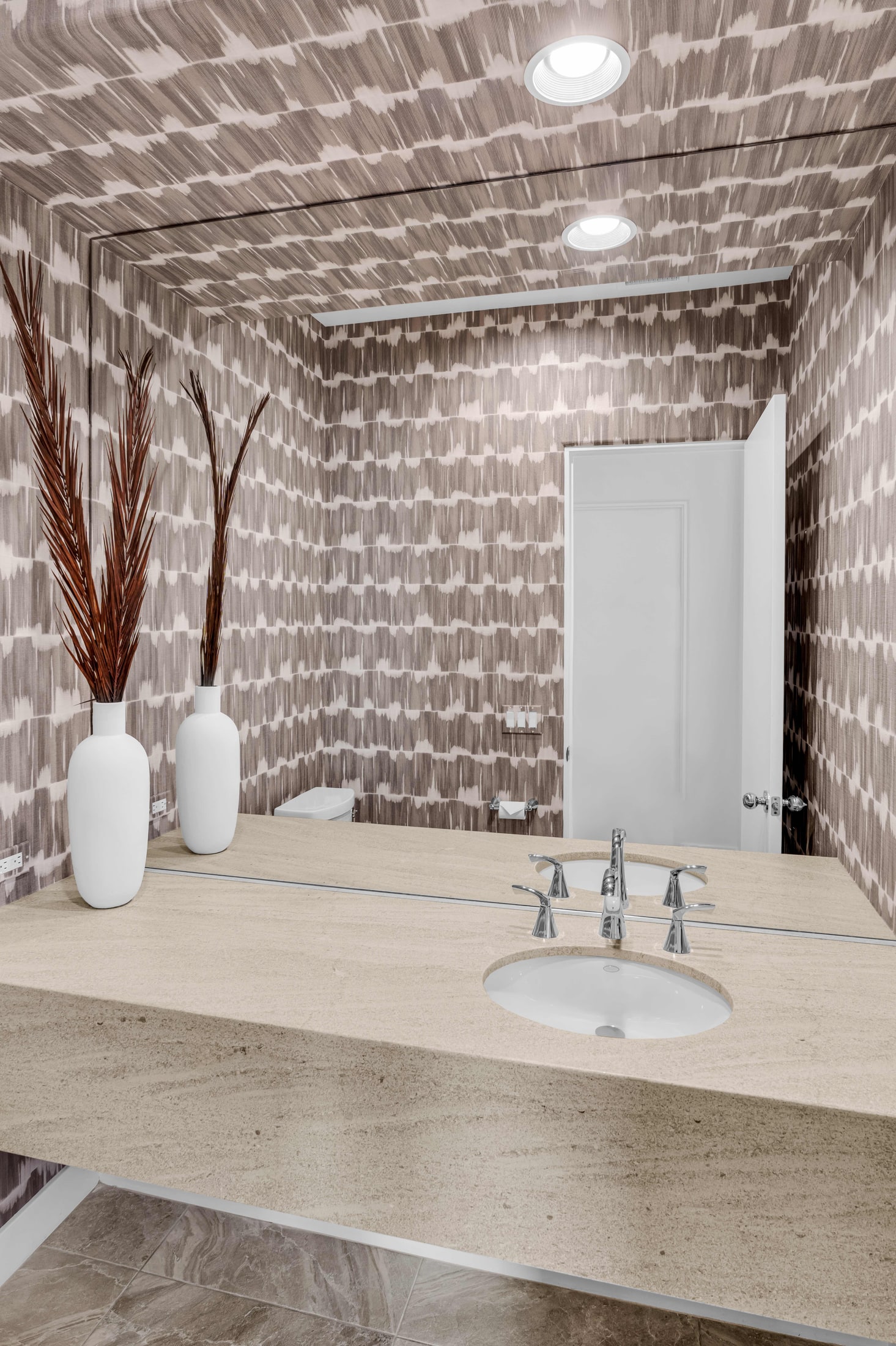 Powder room with dark textured wallpaper and travertine vanity